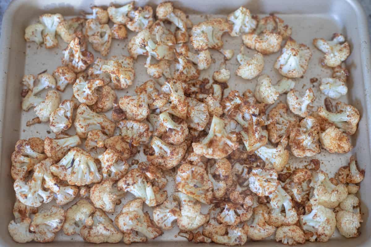 Cooked cauliflower tossed in taco seasoning on a sheet pan. 
