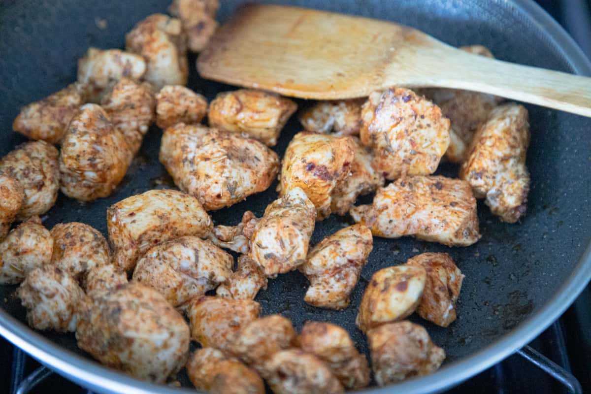 Seasoned chicken chunks cooking in a pan. 