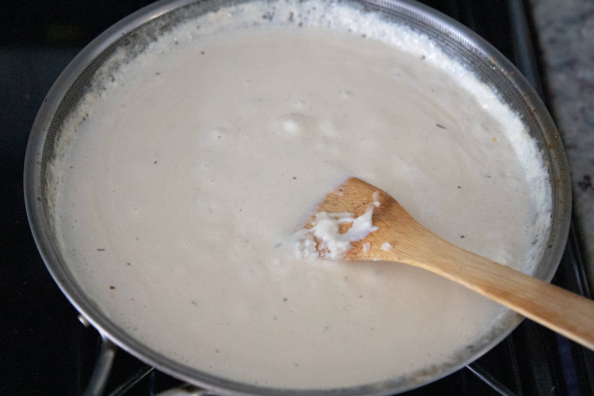 Cream sauce cooking in a pan. It's bubbling slightly. 