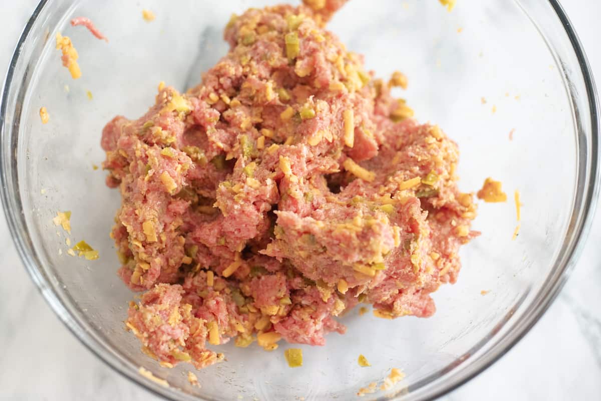 Ground beef and other burger ingredients in a mixing bowl. 