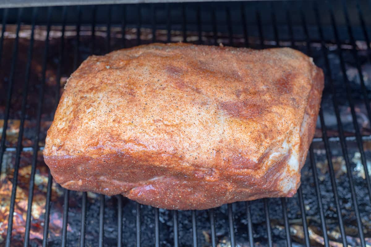 A pork butt on a grill grate with the fat side up. 