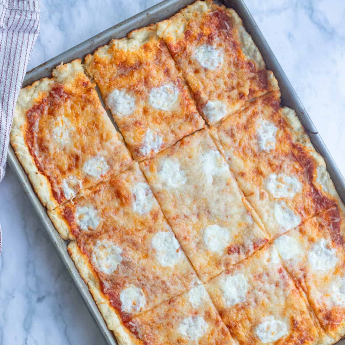 Cafeteria-style school pizza cut into rectangles in a sheet pan.