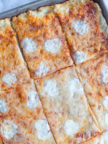 Cafeteria-style school pizza cut into rectangles in a sheet pan.