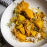 A bowl of Jamaican curry chicken. It's yellow in color and served over rice.