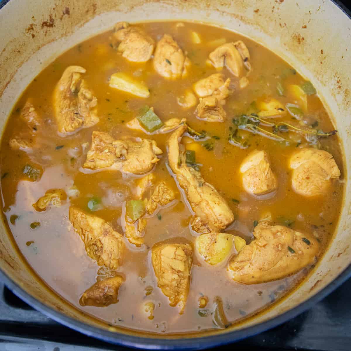 Cooked curry chicken in a dutch oven. The sauce is thickened slightly and brown in color. 