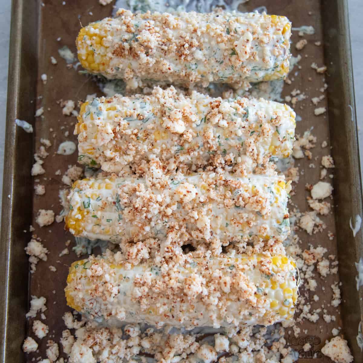 Cheese and a mayonnaise-based sauce on top of corn. 