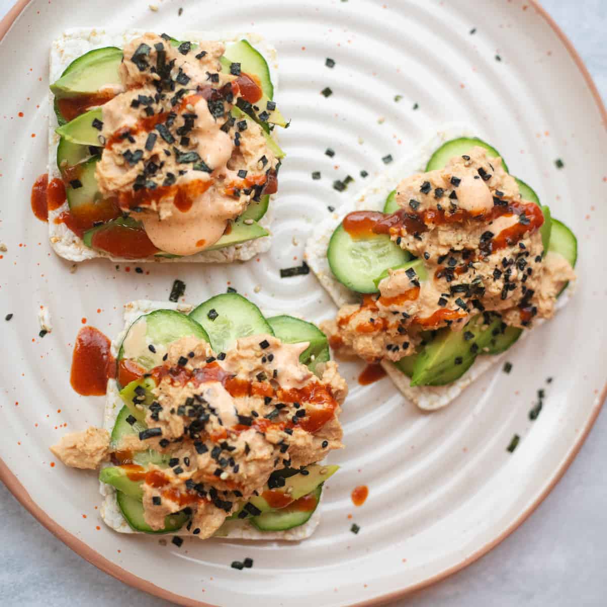 Spicy canned tuna on rice stackers with cucumbers and avocado. 