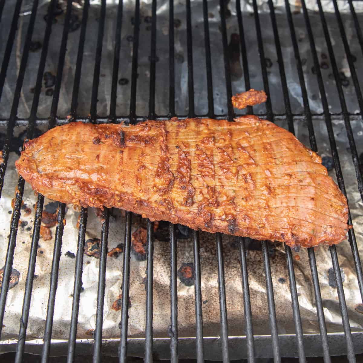 Flank steak cooking on a Traeger grill. 