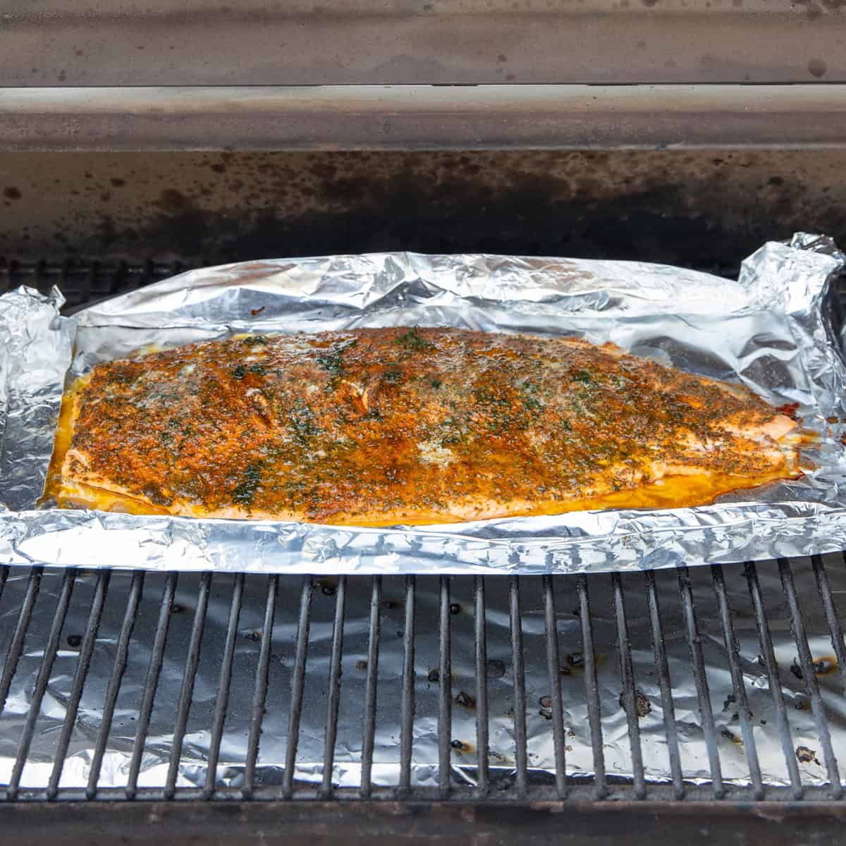 Cooked salmon on a Traeger. It's topped with fresh dill and melted butter. 