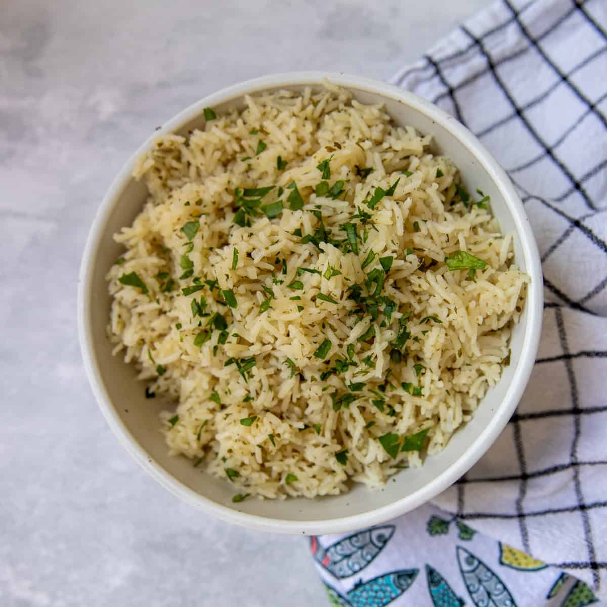 Cooked basmati rice in a serving bowl topped with chopped fresh parsley.